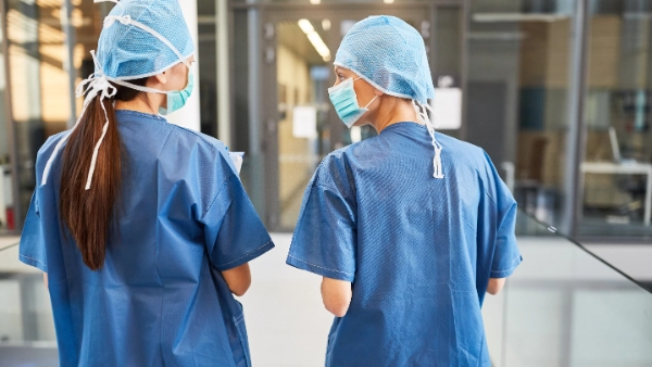 Two women in blue scrubs talking to each other